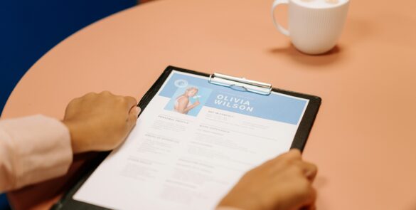 Professional CV writing service showing a recruiter reviewing a polished curriculum vitae on a clipboard next to a coffee cup.