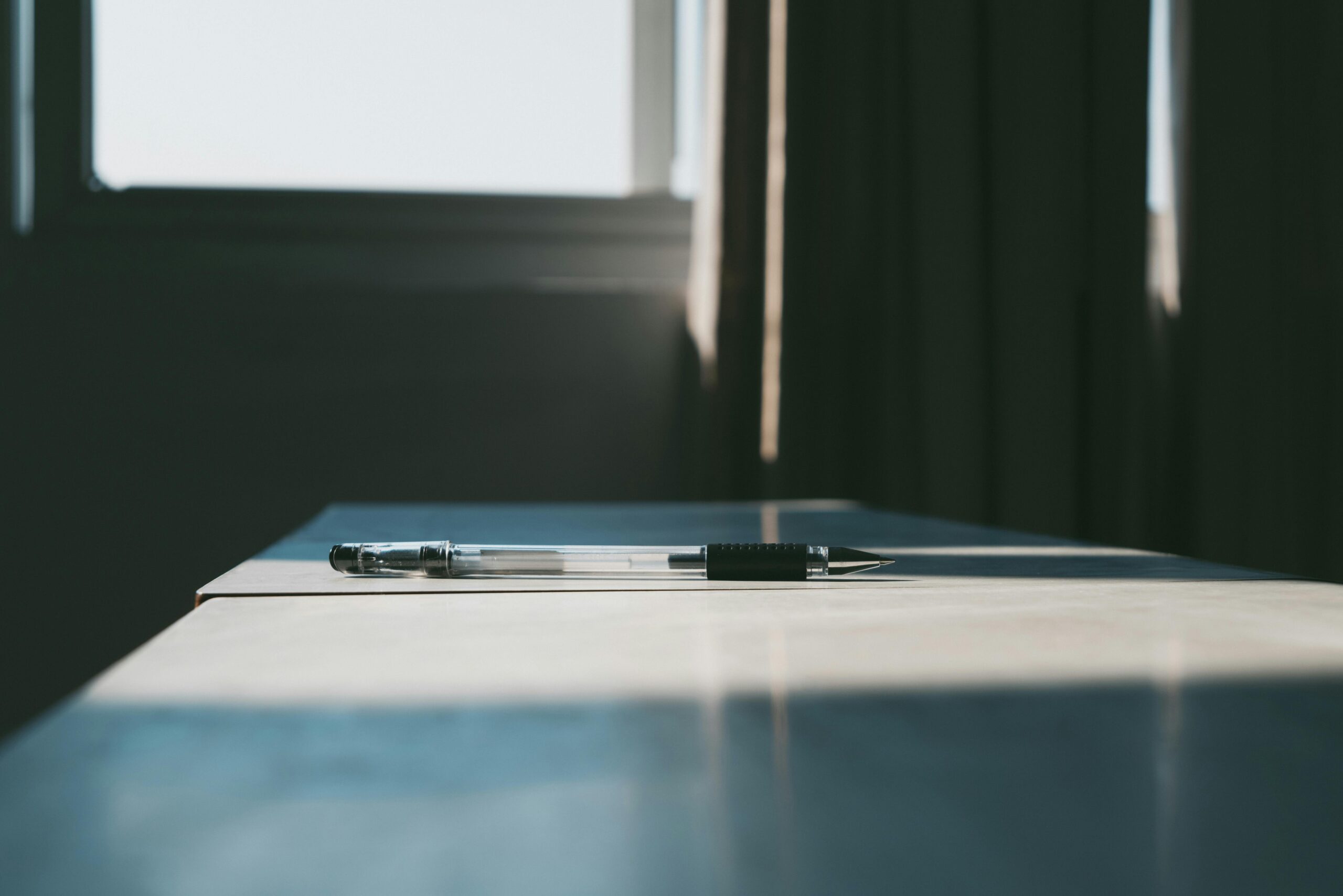 A pen resting on a desk in natural light, symbolizing professional CV writing services by a curriculum vitae specialist.